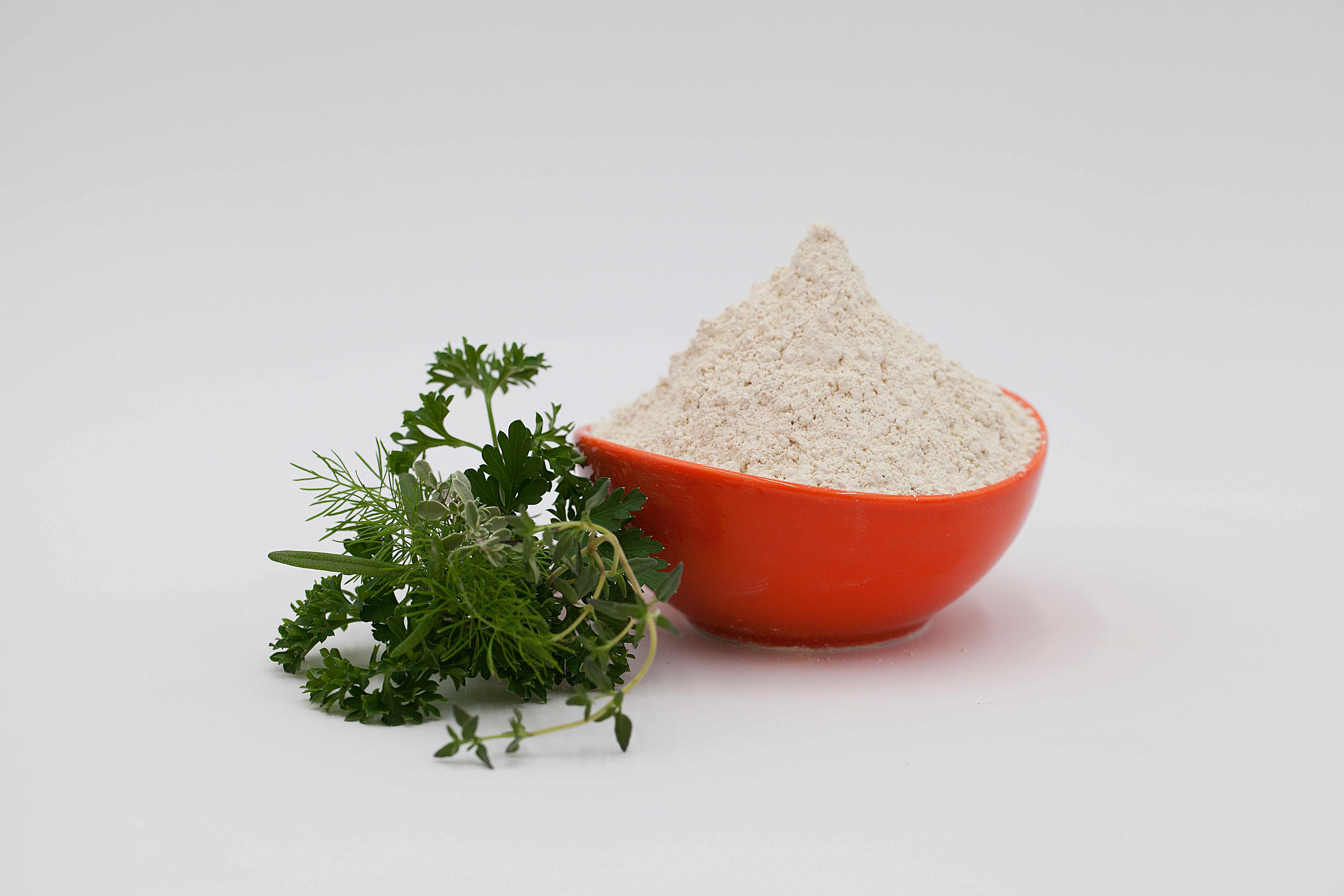 Protein powder in an orange bowl with fresh herbs