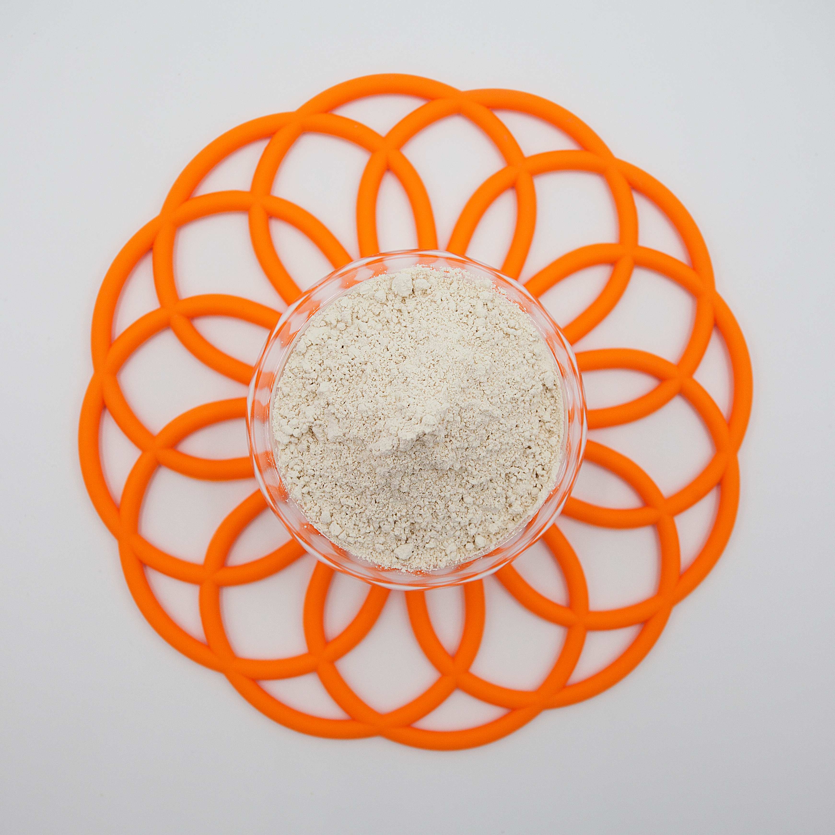 Protein powder in glass bowl on orange geometric trivet